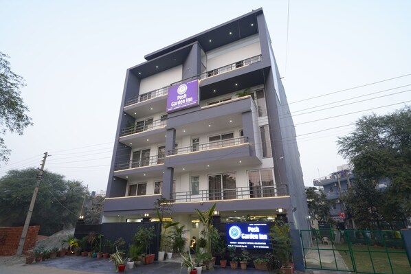 A multi-story building with a prominent sign for "Pash Garden Inn." - Posh Garden Inn (Gurugram)