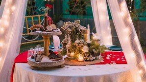A table set for a meal with various food items and a candle centerpiece. - Posh Garden Inn (Gurugram)