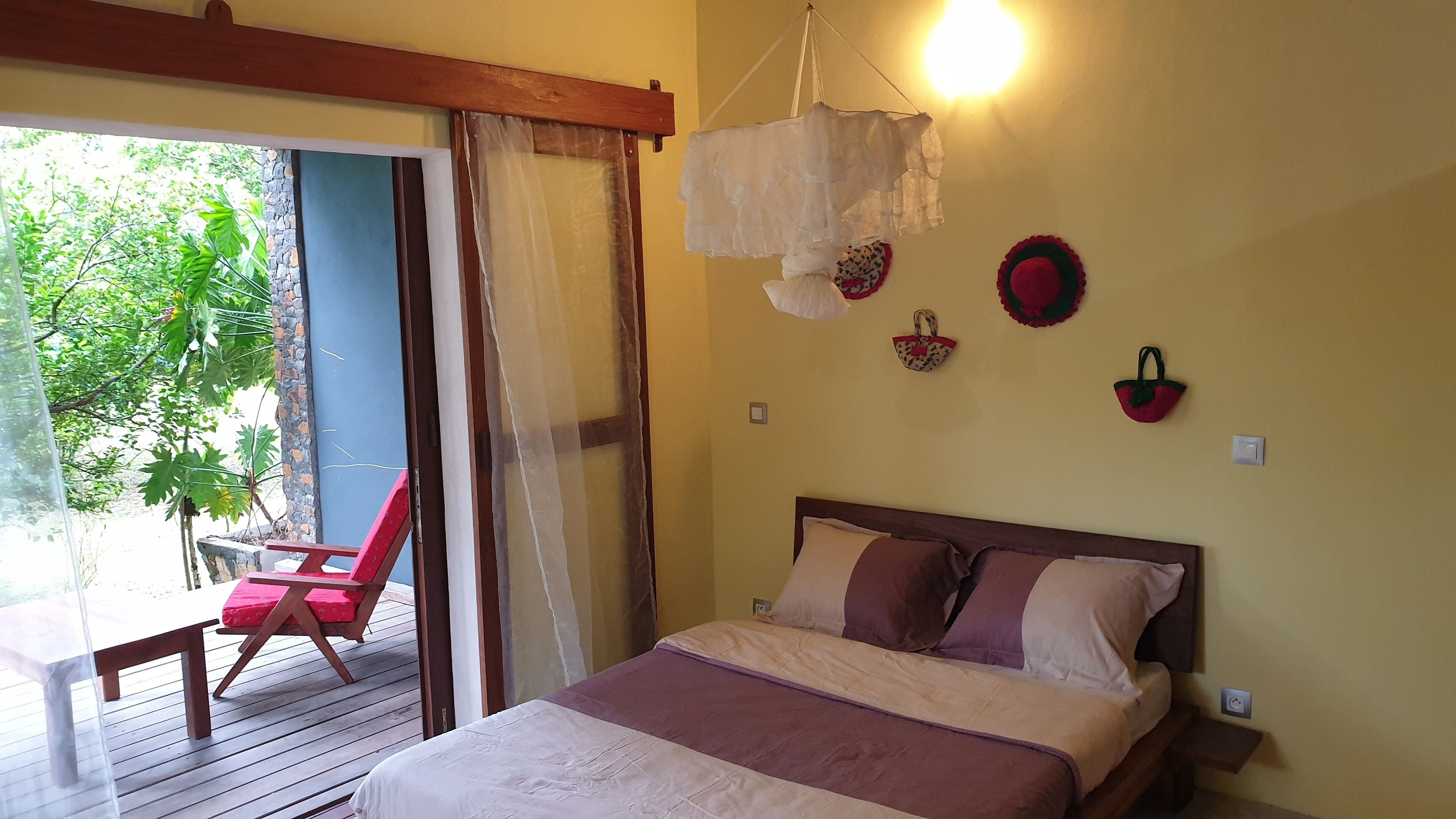 Un dormitorio con cama, una silla y vistas al verdor exterior.
