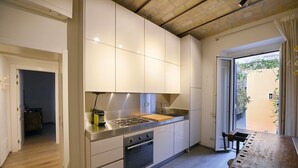 Une cuisine moderne avec des meubles blancs, un plan de travail en acier inoxydable et une table en bois.