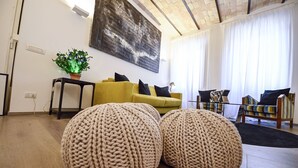 Un salon avec un canapé jaune, un grand tableau abstrait et une plante en pot.