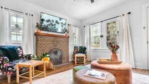 Una sala de estar con chimenea de ladrillo, un sofá, una silla y una mesa de centro.