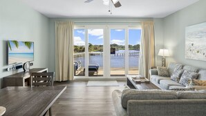 A living room with a large window, a ceiling fan, a TV, and a sofa.
