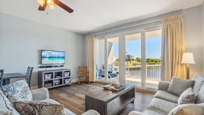 A spacious living room with a wooden coffee table, grey sofas, and a television on the wall.