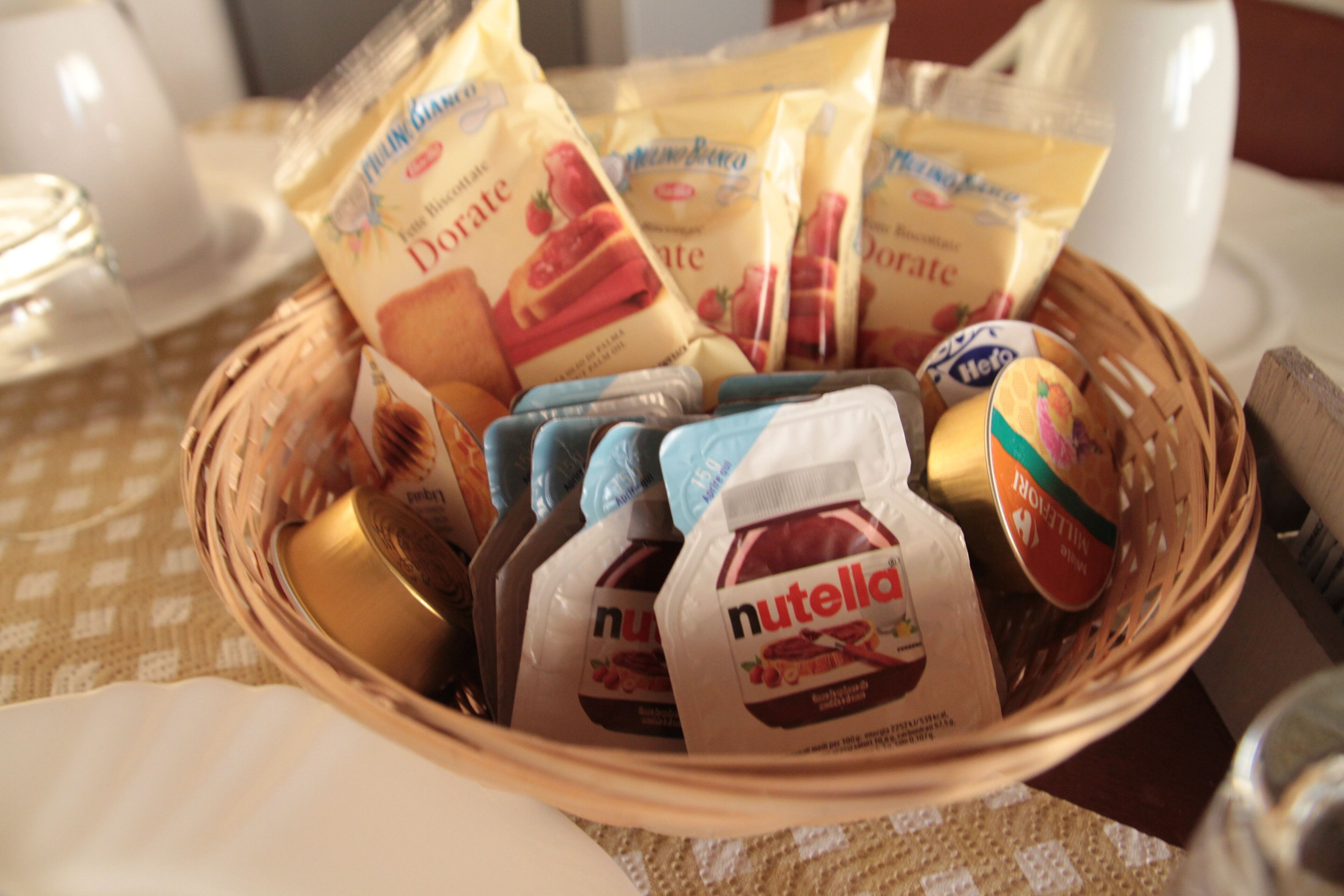 Ein Korbkörbchen mit verschiedenen Lebensmitteln, darunter Gläser Nutella und Beutel Danone Joghurt.