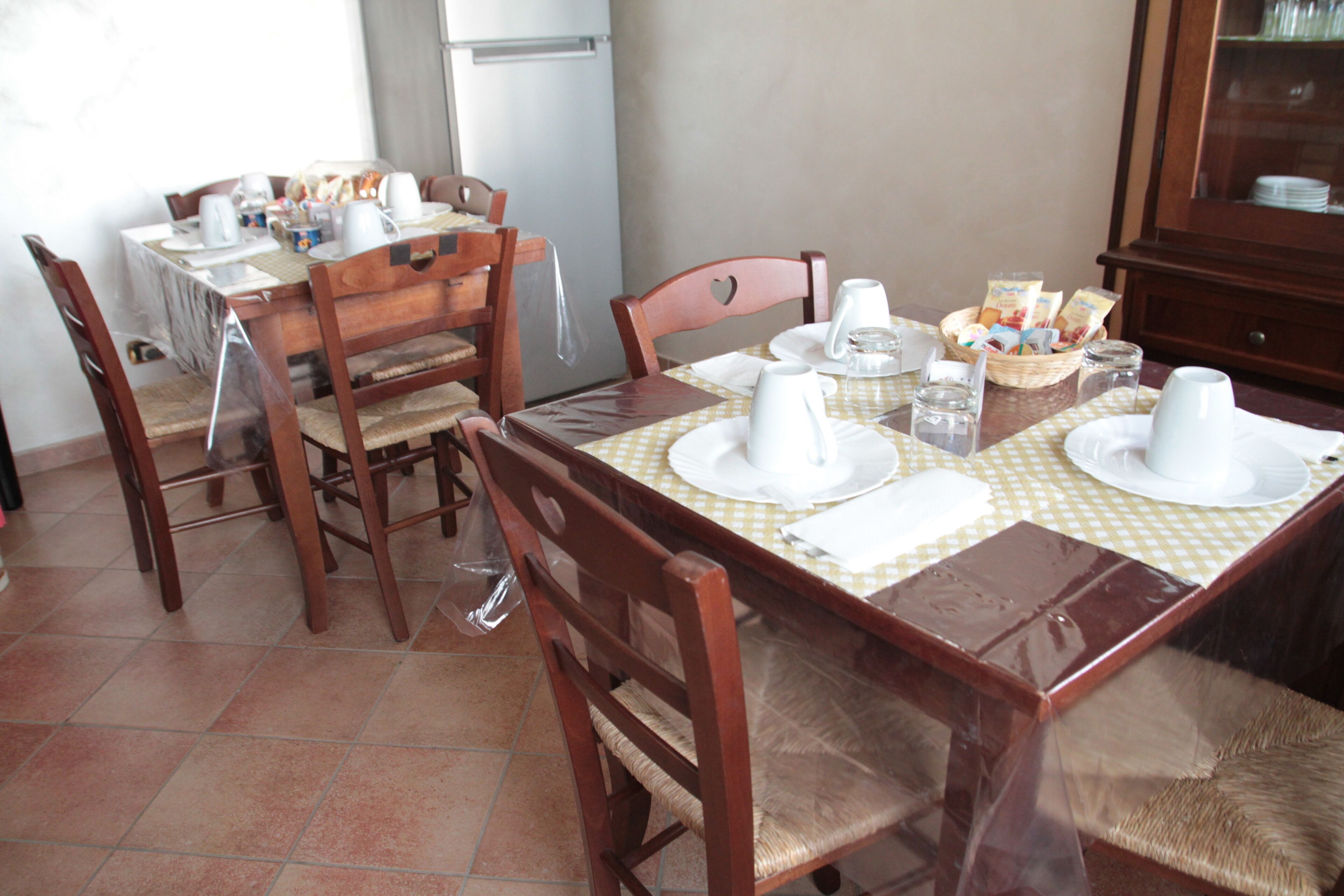 A dining area with a checkered tablecloth, wooden chairs, and a cabinet in the background.