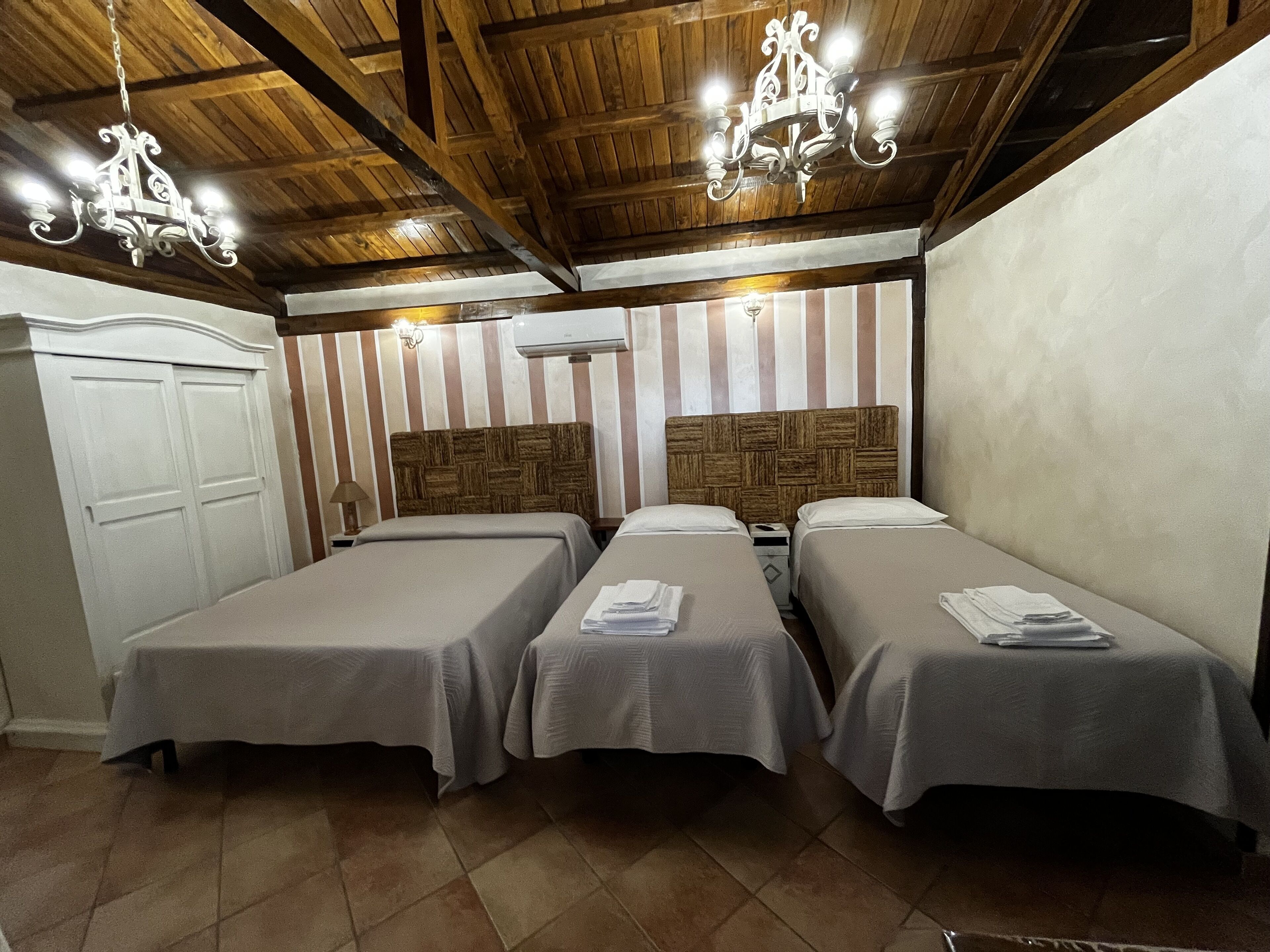 A hotel room with two beds, wooden ceiling beams, and striped wallpaper.