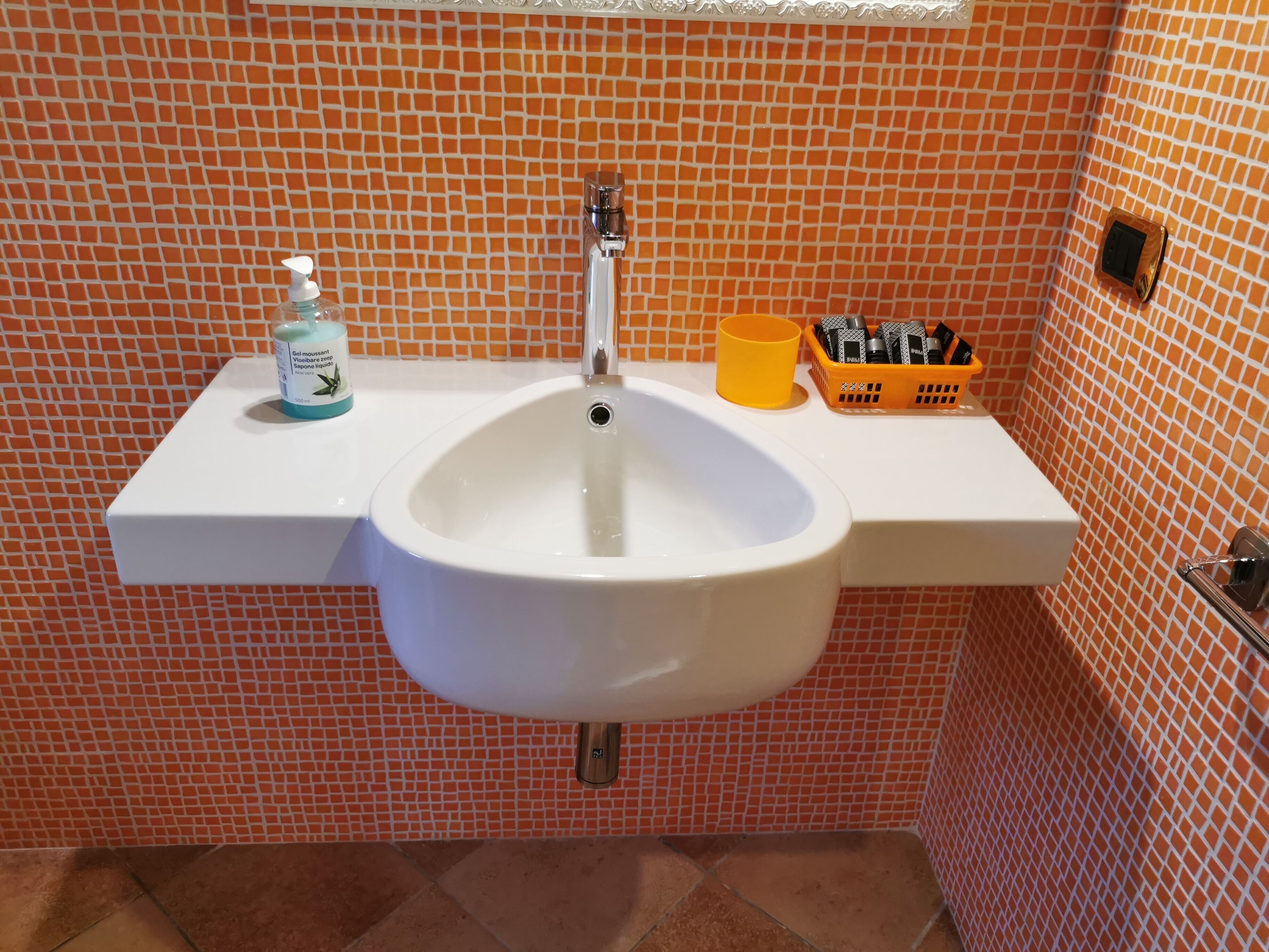 A bathroom with a white sink, a soap dispenser, and a toothbrush holder on a white countertop.