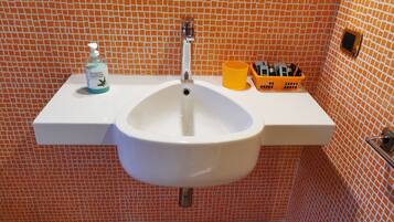 A bathroom with a white sink, a soap dispenser, and a toothbrush holder on a white countertop.