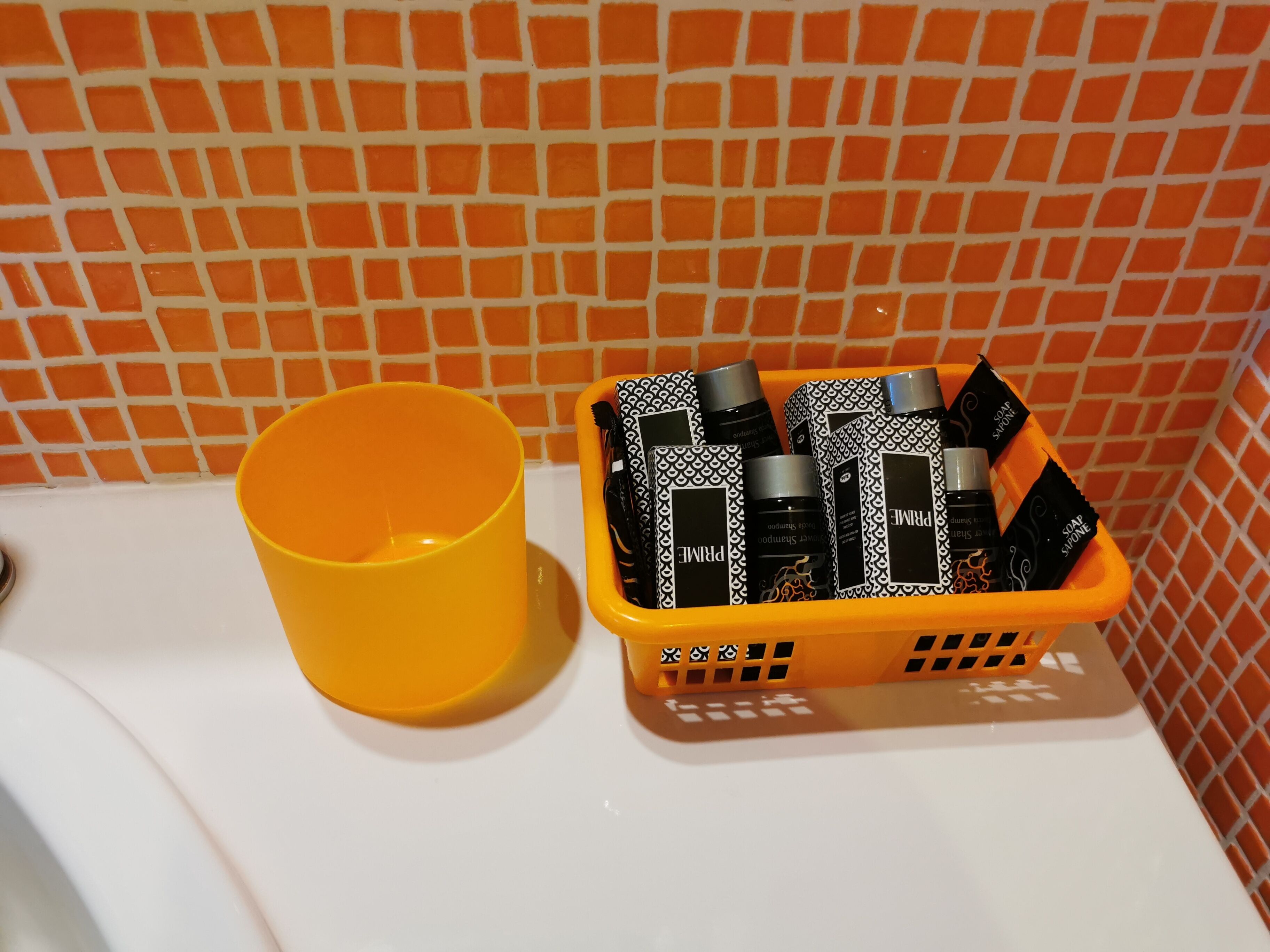 Un baño con una taza amarilla y una cesta con artículos de aseo.