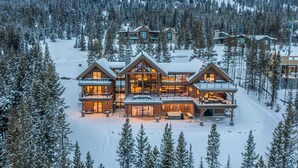 A large, multi-story lodge with a prominent central building featuring large windows and a balcony. - Newly Built | Ski-in/Ski-out | Hot Tub (Big Sky)