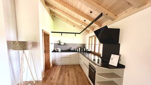 A modern kitchen with wooden flooring, a black countertop, and a built-in oven. - Ferienwohnung Mia, 100m², 2 Schlafzimmer, Wlan (Siegsdorf)