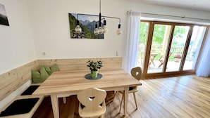 Un comedor con una mesa de madera, sillas, un banco y una planta en maceta.