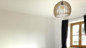 Una cama de madera con ropa de cama blanca, una mesita de noche y una ventana con cortinas.