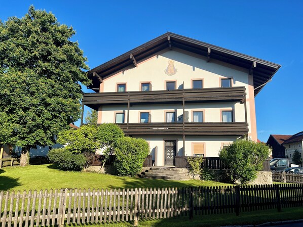 A multi-story building with a balcony, a front door, and a small garden area. - Ferienwohnung Almglück, Separates Schlafzimmer, Küche, Terrasse, TV, Wlan (Rottau)