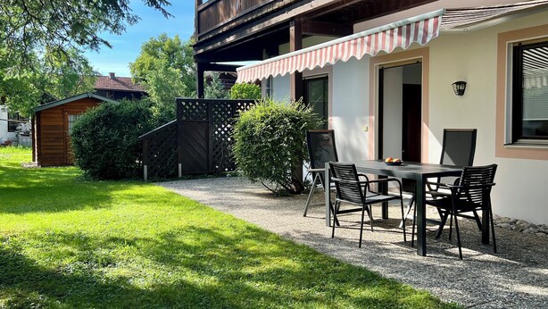 A patio with a table and chairs, a wooden fence, and a small shed. - Ferienwohnung Almglück, Separates Schlafzimmer, Küche, Terrasse, TV, Wlan (Rottau)