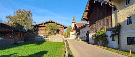 En typisk europeisk bys gata med trähus, en kyrka med ett klocktorn och en klarblå himmel.