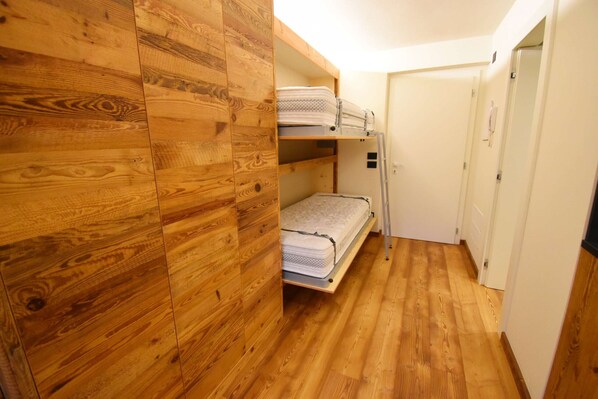A compact room with wooden paneling and a bunk bed.