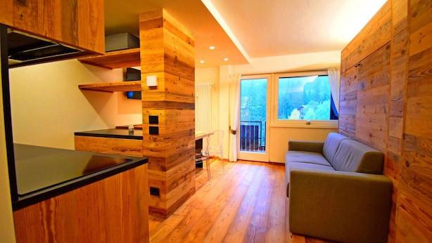 A modern interior with wooden paneling, a sofa, and a window with a view.