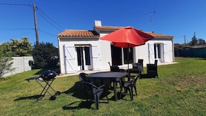 Una casa con patio, una parrilla y mobiliario exterior.