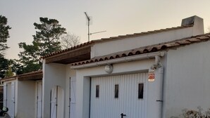 Una hilera de edificios blancos con techos de tejas, cada uno con una puerta cerrada y una pequeña ventana. Un letrero en una puerta dice 