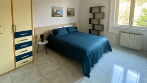 A bedroom with a bed, a nightstand, a lamp, a wardrobe, a window, and two paintings on the wall. - 5 minutes from the Valley of the Temples, apartment with free parking (Agrigento)