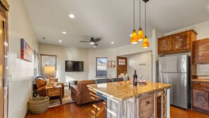 A modern kitchen with a central island, wooden cabinets, and a stainless steel refrigerator. - Red Rock Oasis I Large Patio I Pool & Hot Tub I Views (Moab)