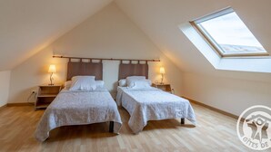 Ein Schlafzimmer mit zwei Betten, einem Oberlicht und Holzboden.