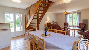Ein Essbereich mit einer Holztreppe, einem Tisch mit Stühlen und einer Couch.