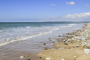A beach with a sandy shore and scattered rocks. - 5 The Crescent (Caernarfon)