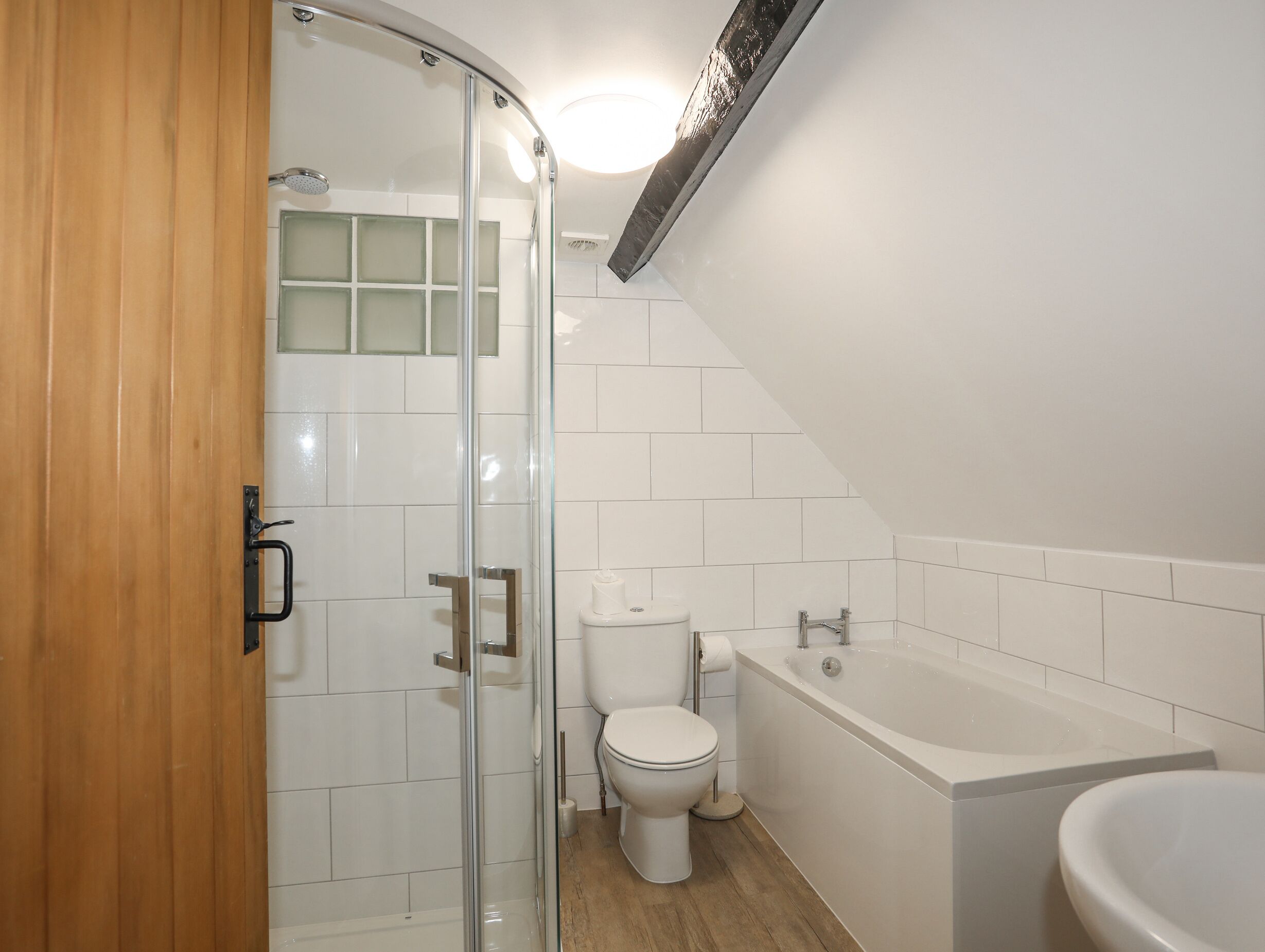 Een moderne badkamer met een douchecabine van glas, een toilet, een bad en een wastafel.