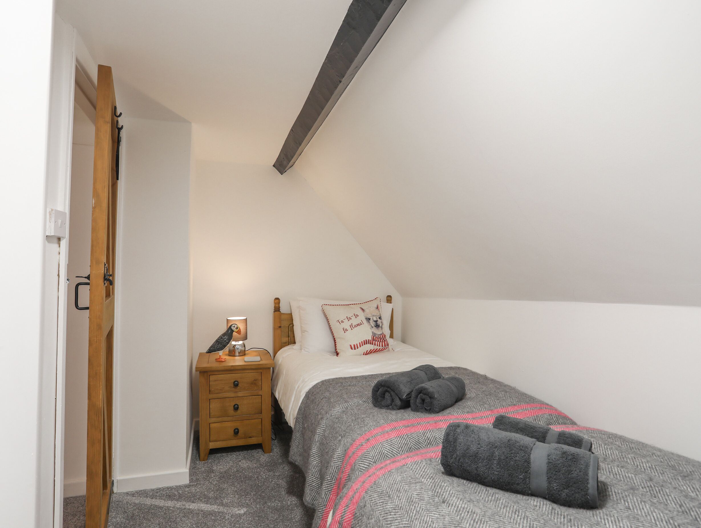 A bedroom with a bed, a nightstand, a lamp, and a door.