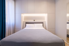 Una habitación de hotel moderna con una cama bien hecha, una mesita de noche y una pequeña planta en maceta.
