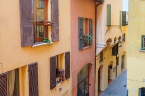 Un edificio de varios pisos con balcones, ventanas con persianas y una pequeña zona de estar al aire libre.