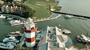 A coastal area with a lighthouse, marina, and buildings with balconies overlooking the water. - Muirfield RANCH/ On #2 Golf Links / Pool / Walk to HARBOUR TOWN/ 4 Bikes / Pet (Hilton Head Island)