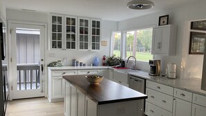 A modern kitchen with white cabinetry, a wooden countertop, and a view of the outdoors through large windows. - Muirfield RANCH/ On #2 Golf Links / Pool / Walk to HARBOUR TOWN/ 4 Bikes / Pet (Hilton Head Island)
