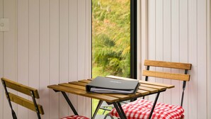 A small table with a notebook, two wooden chairs, and a red and white checkered cushion. - Ryans Ranch by Tiny Away (Belgrove)