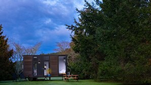 A modern, compact cabin with a small patio area, a dining table, and a seating arrangement. - Ryans Ranch by Tiny Away (Belgrove)
