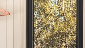 A view through a window to an outdoor area with a wooden table, a candle, and a small jar of reed diffusers. - Mirror Reflections 1 by Tiny Away (Tamborine)