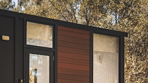 A modern cabin with a glass door, two chairs outside, and a wooden exterior. - Mirror Reflections 1 by Tiny Away (Tamborine)