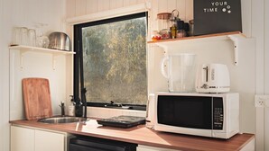A compact kitchen with a wooden countertop, a stainless steel sink, a microwave, and a coffee maker. - Mirror Reflections 1 by Tiny Away (Tamborine)