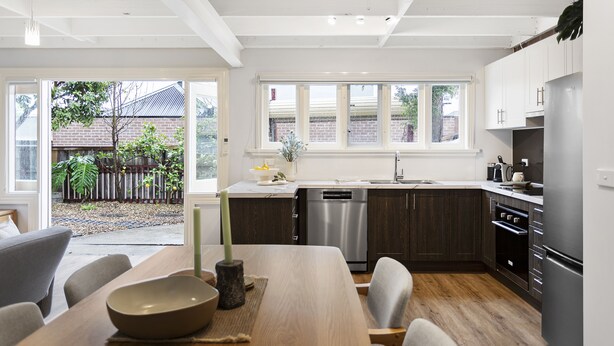 A modern kitchen with dark wooden cabinets, stainless steel appliances, and a large window providing natural light. - Cottage haven close to Ascot Vale cafes, restaurants, racecourse and showgrounds (Ascot Vale)