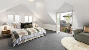 A bedroom with a large bed, a nightstand, a lamp, and a view of the outside. - Cottage haven close to Ascot Vale cafes, restaurants, racecourse and showgrounds (Ascot Vale)