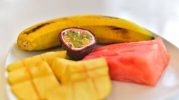 Une assiette avec une banane, une tranche de pastèque et la moitié d’un fruit de la passion.
