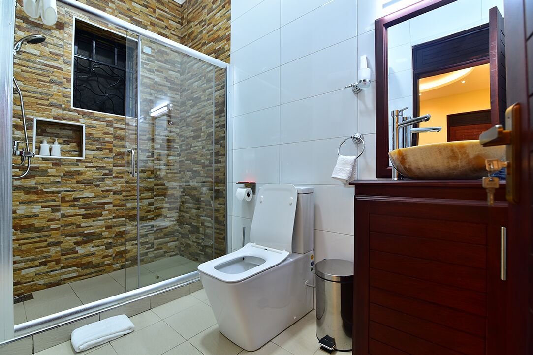 A bathroom with a glass-enclosed shower, a white toilet, and a wooden vanity with a sink.