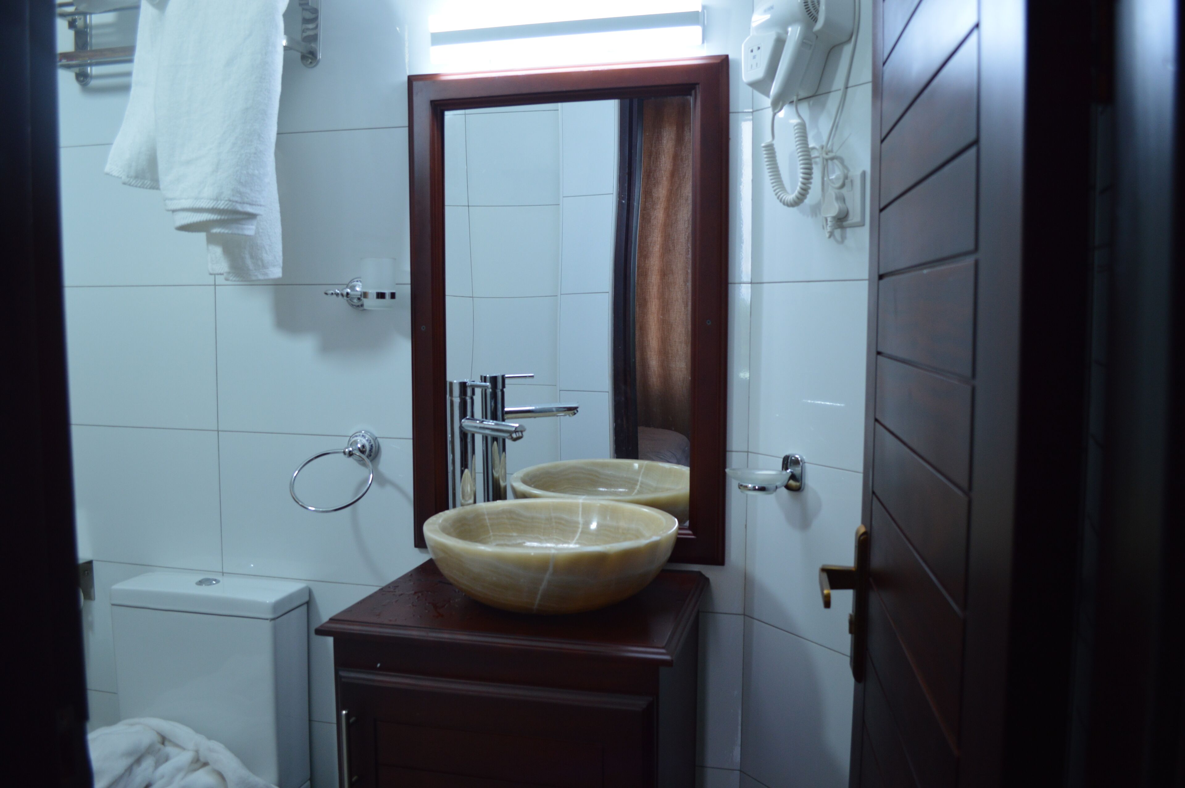 Une salle de bain avec un meuble-lavabo en bois, deux vasques, un miroir, un porte-serviettes et des toilettes.
