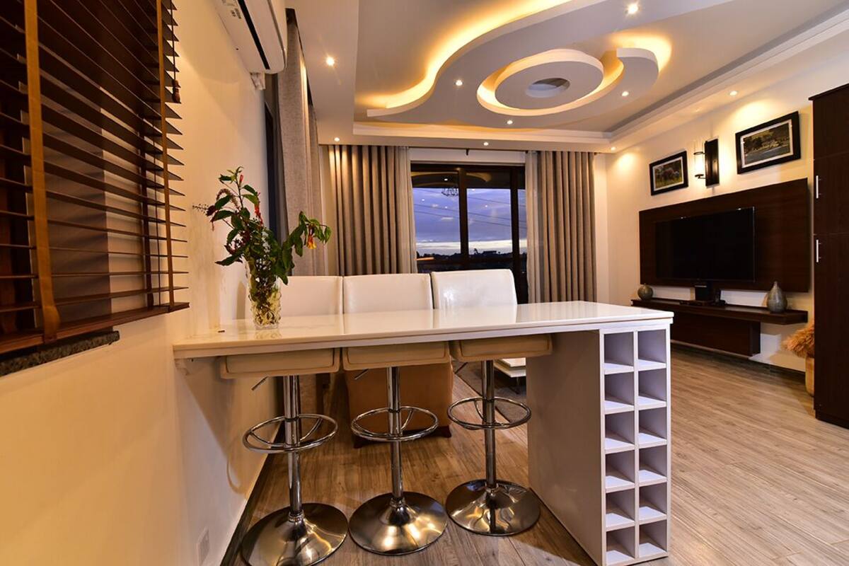 A modern kitchen with a bar area, including a white countertop, bar stools, and a wine rack.