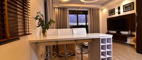 A modern kitchen with a bar area, including a white countertop, bar stools, and a wine rack.