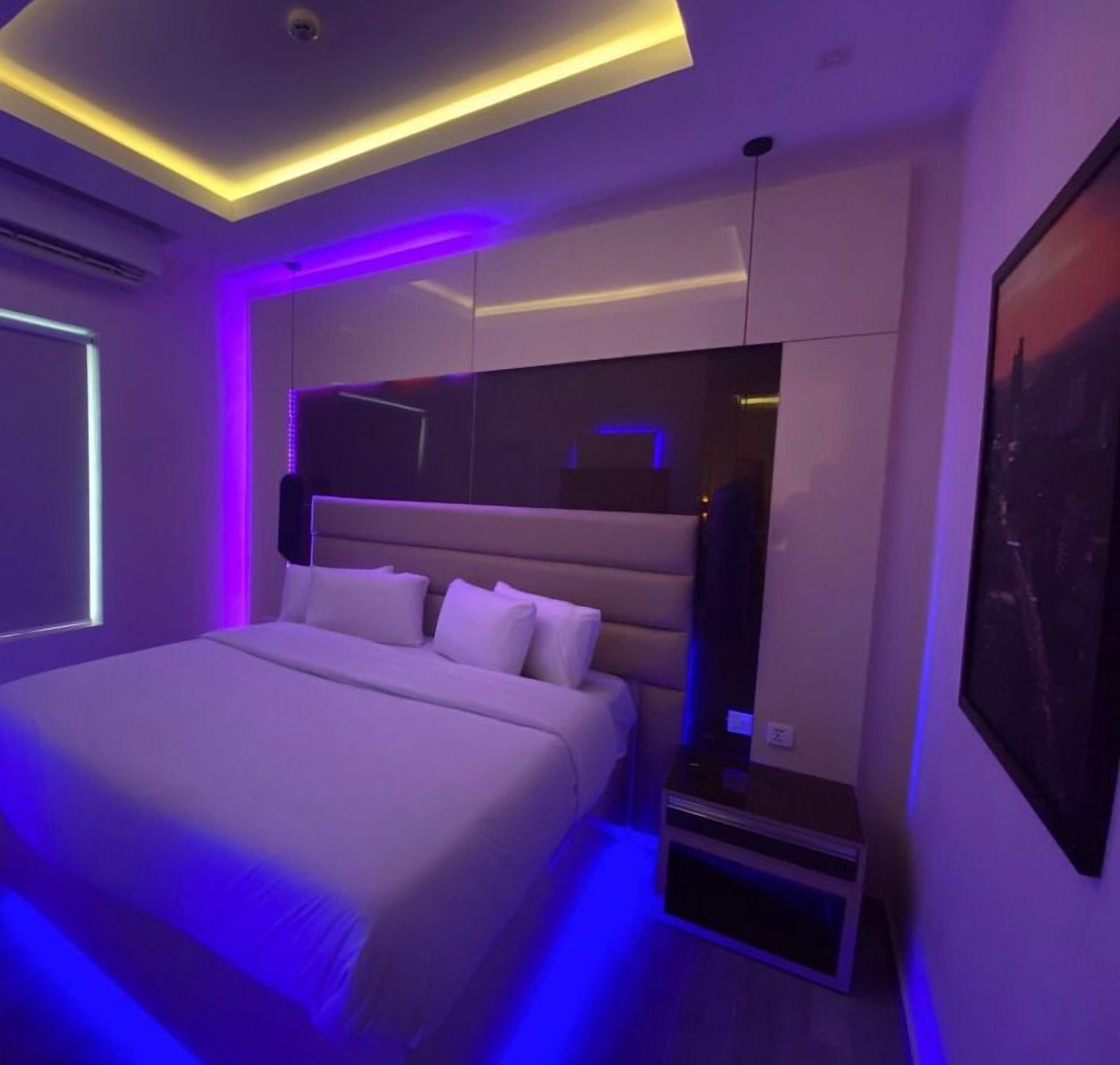 Un dormitorio moderno con una cama grande, almacenamiento integrado e iluminación ambiental.