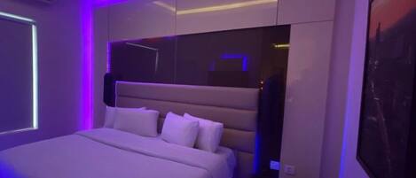 Un dormitorio moderno con una cama grande, almacenamiento integrado e iluminación ambiental.